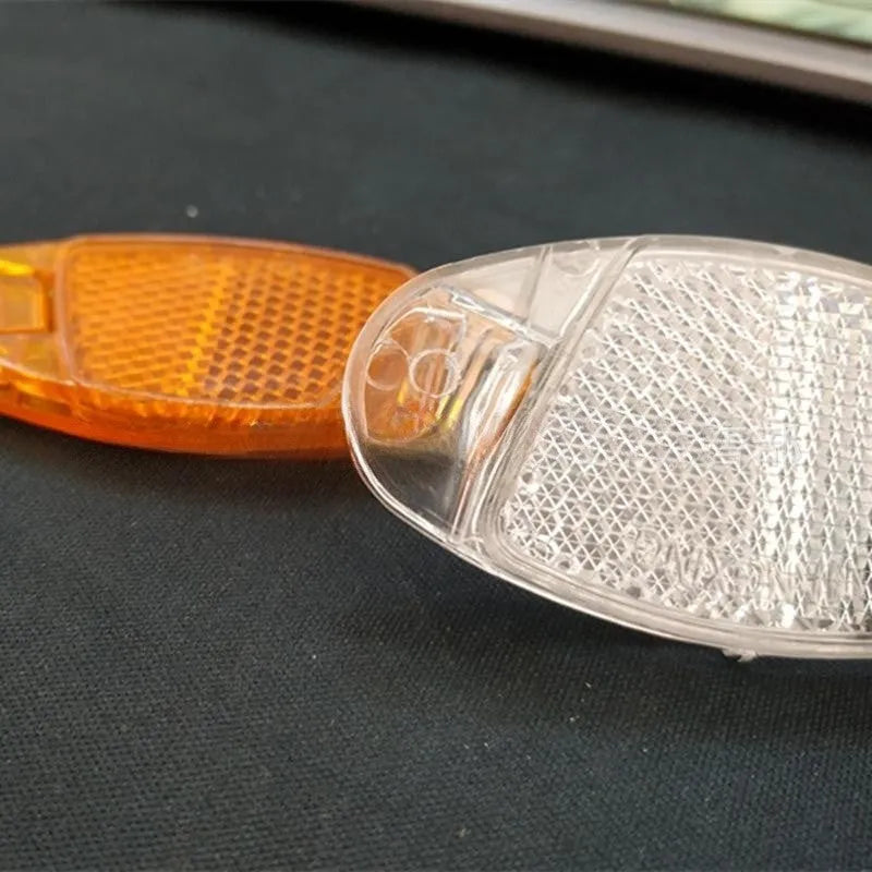 White and yellow plastic bicycle reflector spoke decorations measuring 7.2cm by 3.5cm