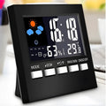 Black digital alarm clock thermometer displaying temperature and time on a desk