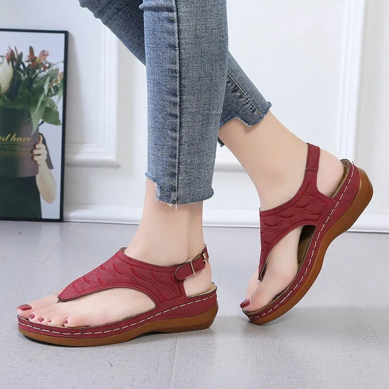Women's red wedge heel flip flop sandals with an adjustable buckle strap on a white background.