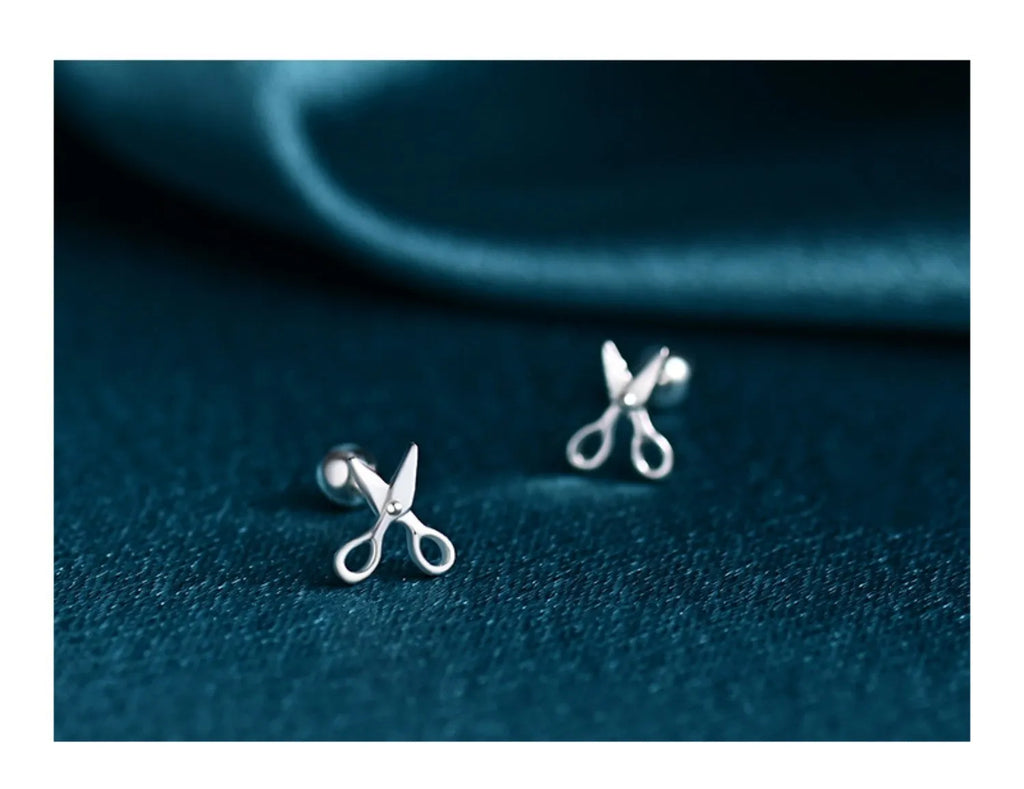 A pair of pure silver screw-back earrings for women with a mini scissors design on the fastening.