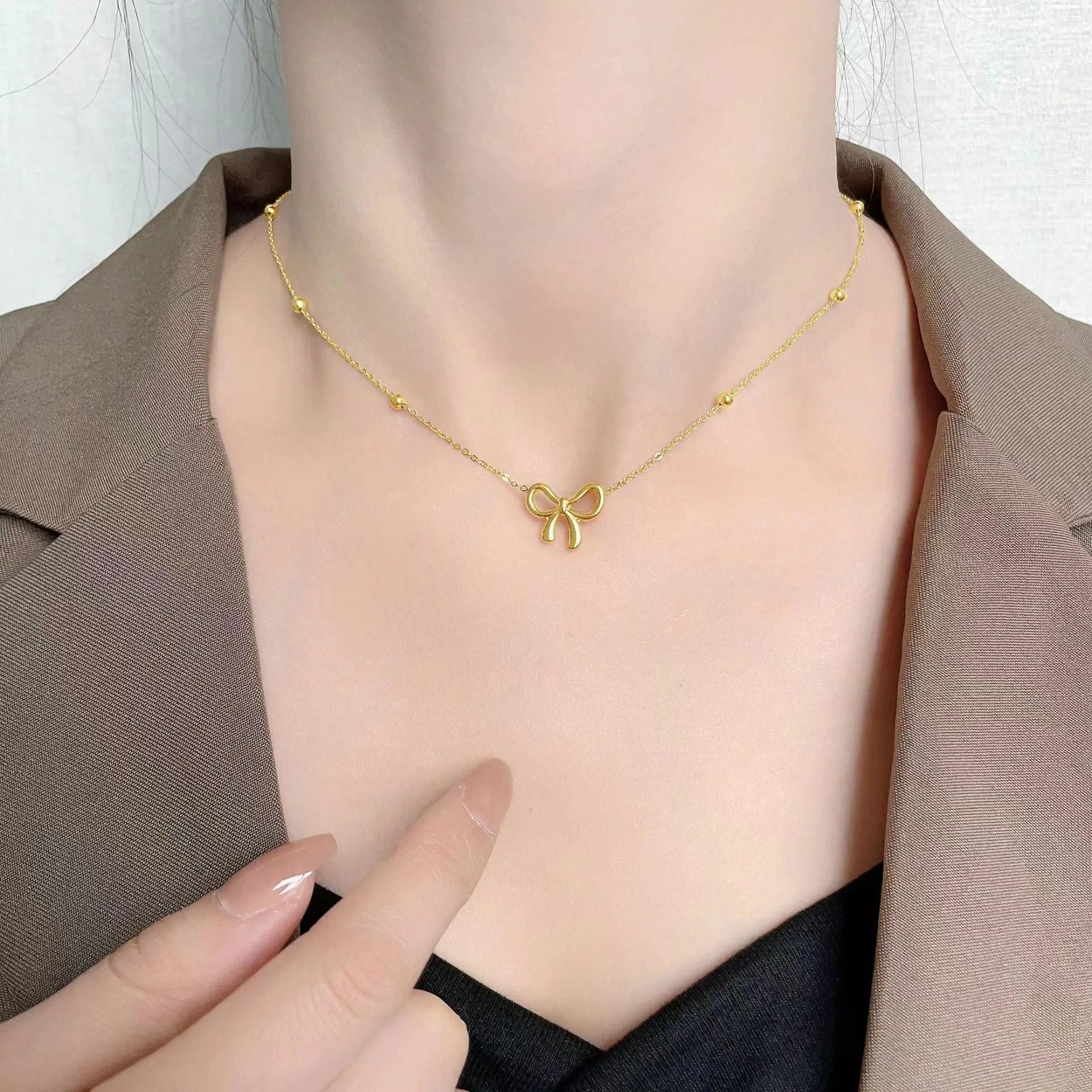 Gold-coloured bow pendant necklace on a cross-link chain, adjustable from 41 to 50 cm.