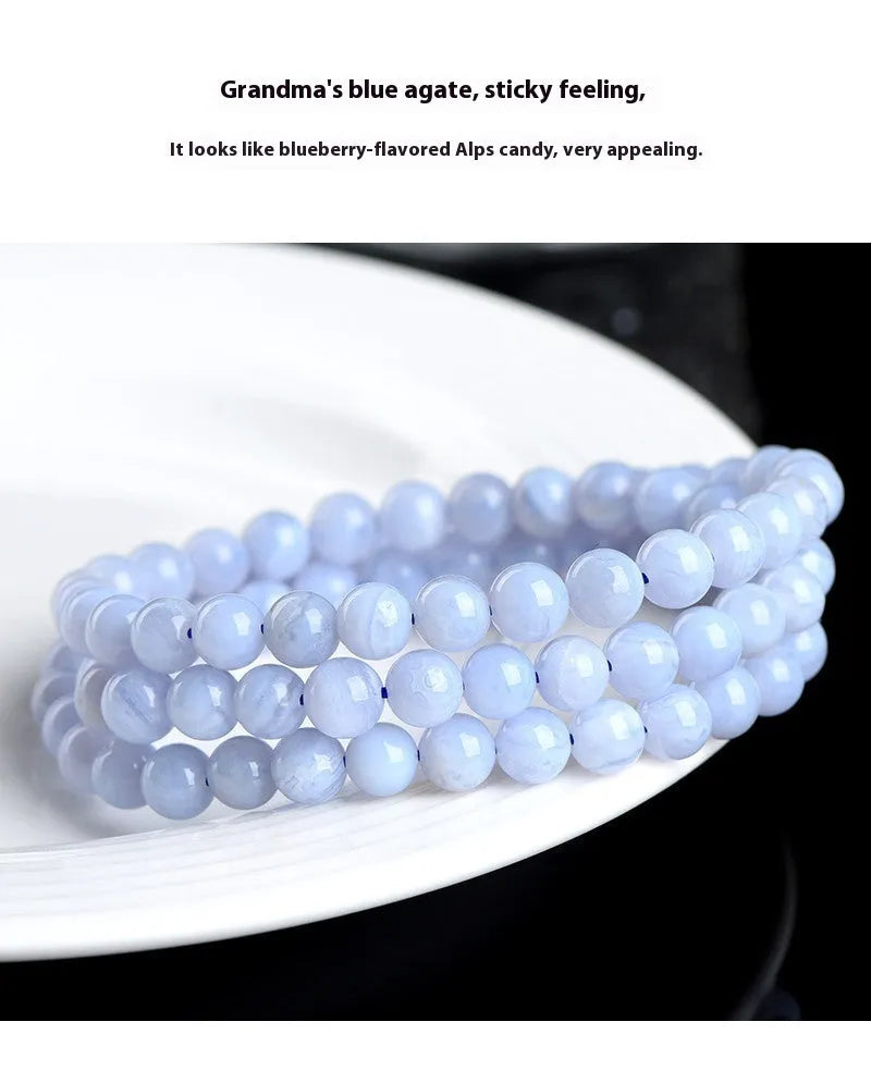 Close-up of a blue agate bracelet with scattered beads and striped spheres on a wrist.