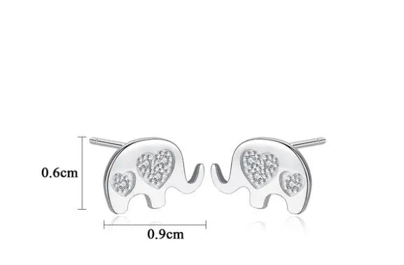 Small geometric silver stud earrings with gold or silvery finish on a grey background.