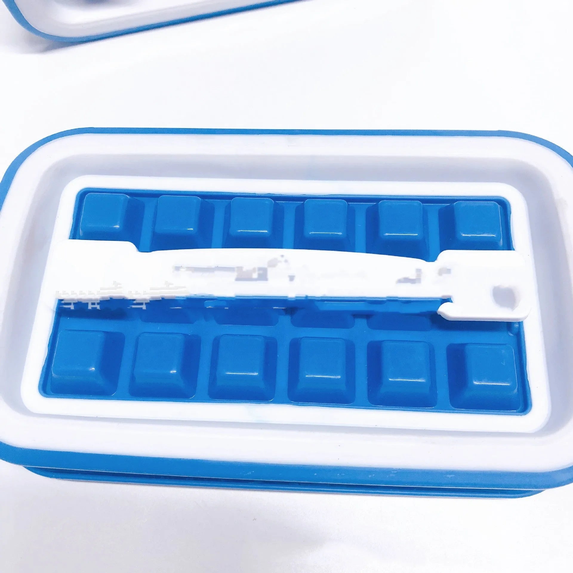 Blue silicone ice cube tray with 36 grids on a white background showing lid and one removed cube