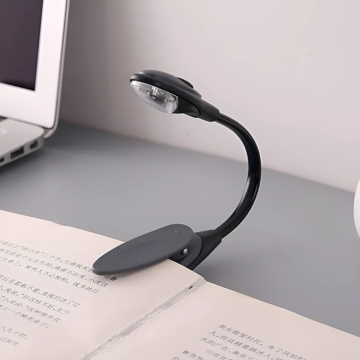 Mini clip-on LED book light with 26cm arm attached to a hardcover book