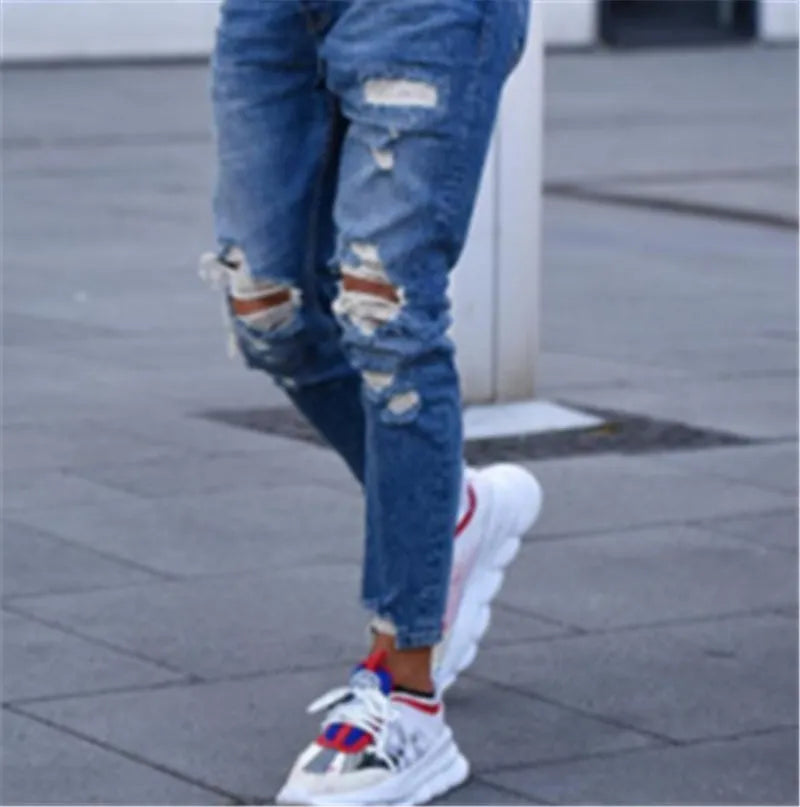 Men's deep blue cotton jeans with a distressed hole design laid flat.