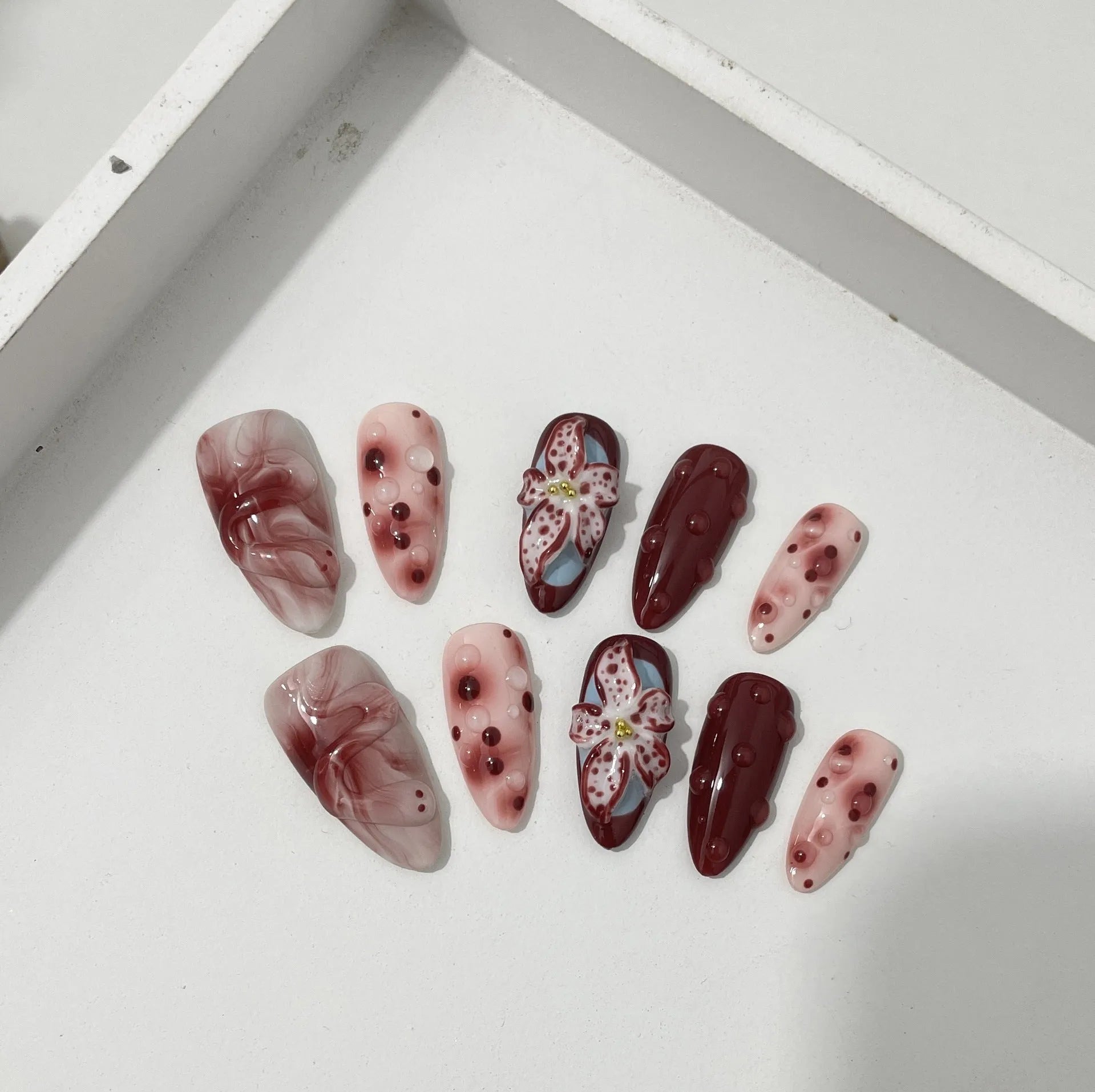 Hand-painted 3D carved press-on nails in mid-length almond shape with floral and pattern designs.