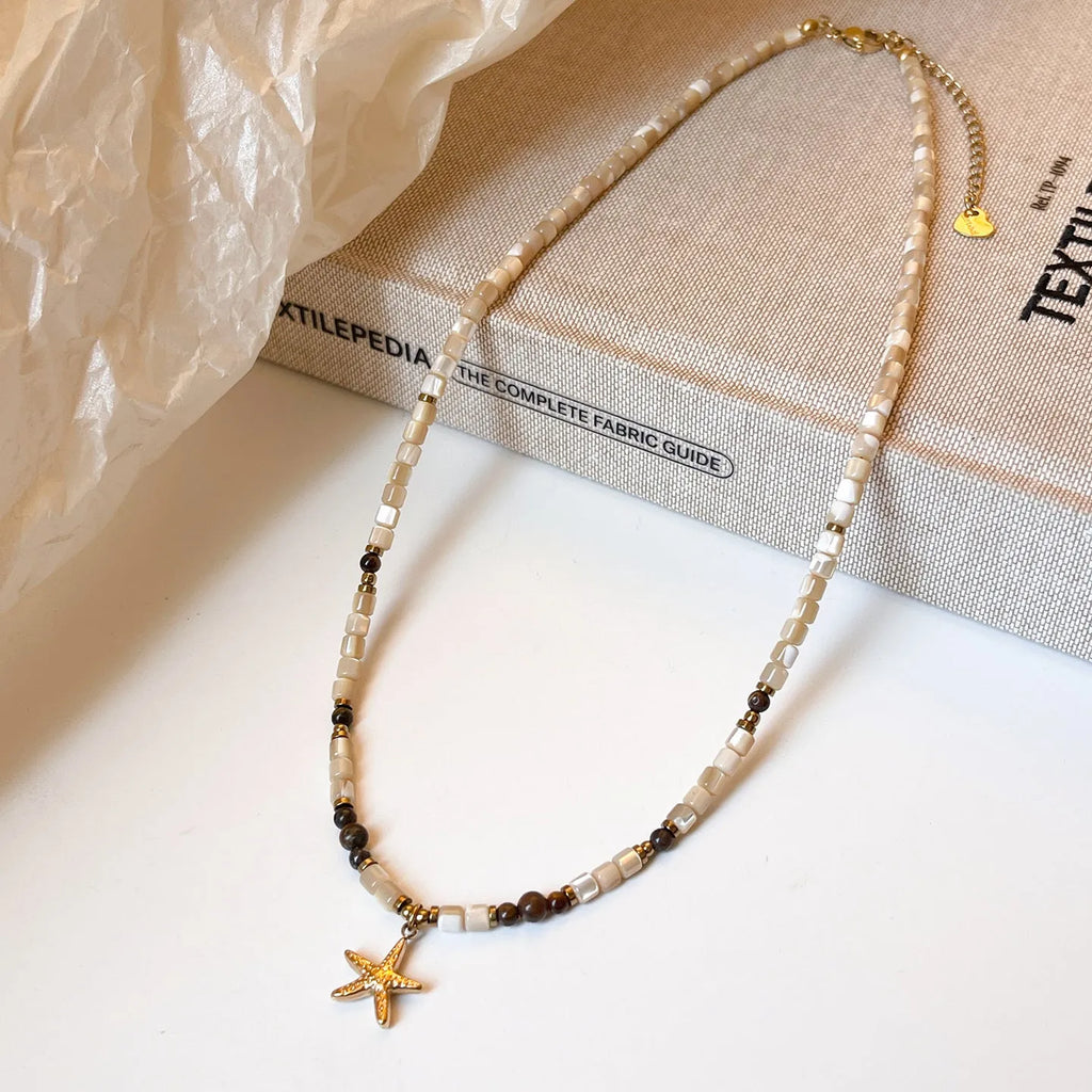 Close view of titanium steel starfish pendant necklace with natural shell and tigereye bead on a woman, Maillard colour, 41-50cm chain