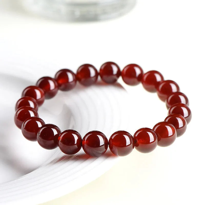 Natural orange red garnet crystal bracelet with Ruyi charms on a white background.