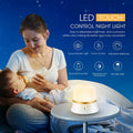 White bedside night light with touch controls for dimming and changing RGB colours on a table.