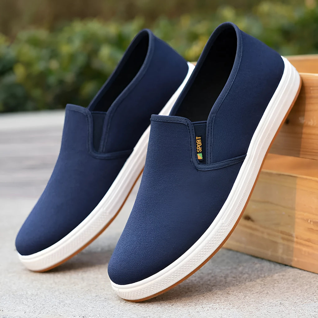Men's black slip-on canvas trainers with round toe and low-top design on a white background