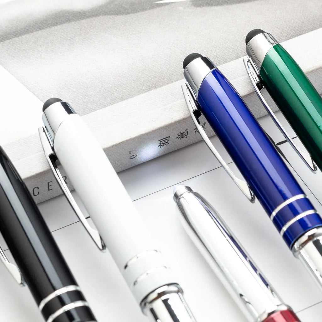 Red metal ballpoint pen with a capacitive stylus tip and built-in LED light on a desk.