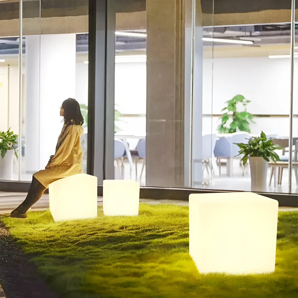 A white, square LED cube light stool with a modern design, shown outdoors on a patio.