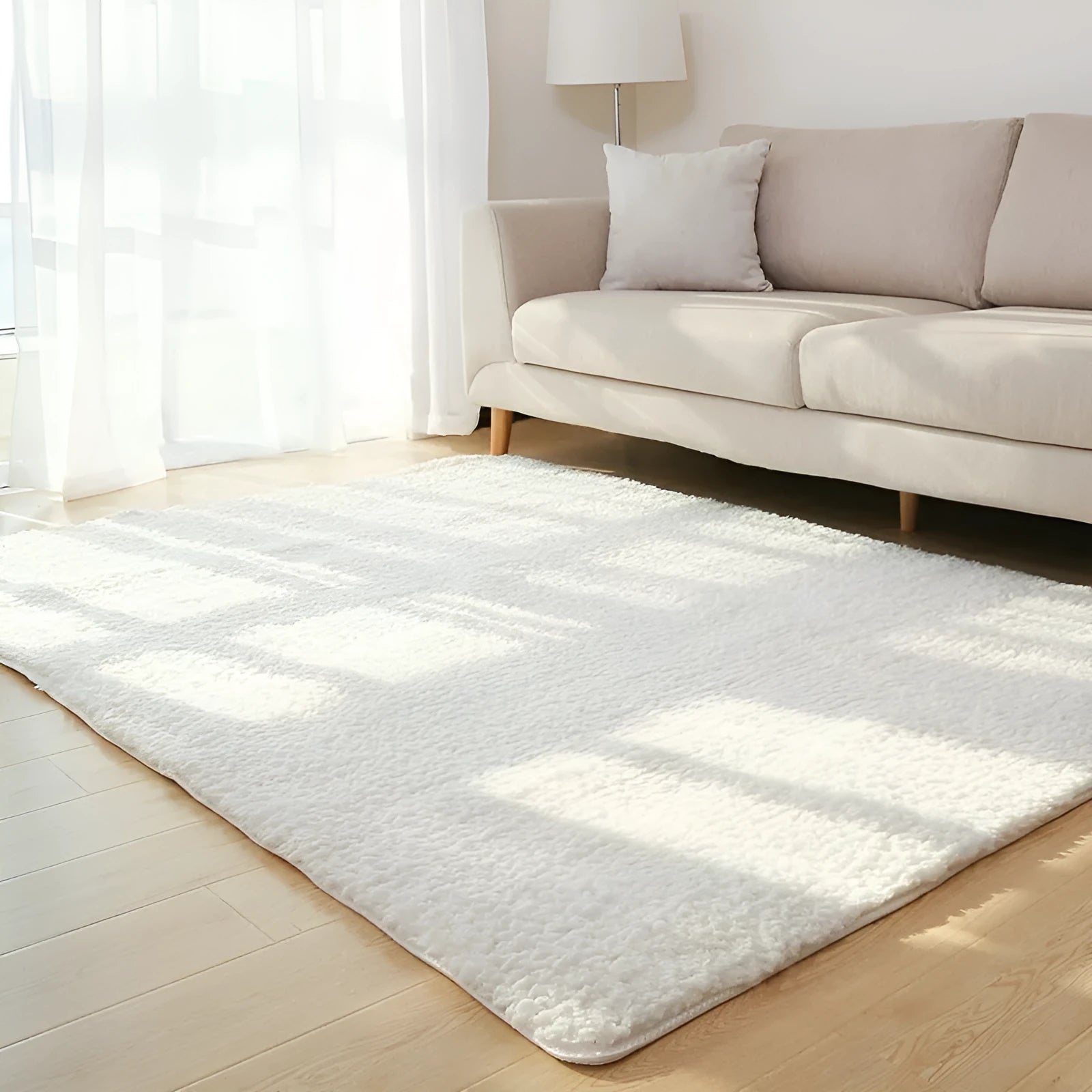 White fluffy plush rectangular area rug with a non-slip dotted bottom on a wooden floor.