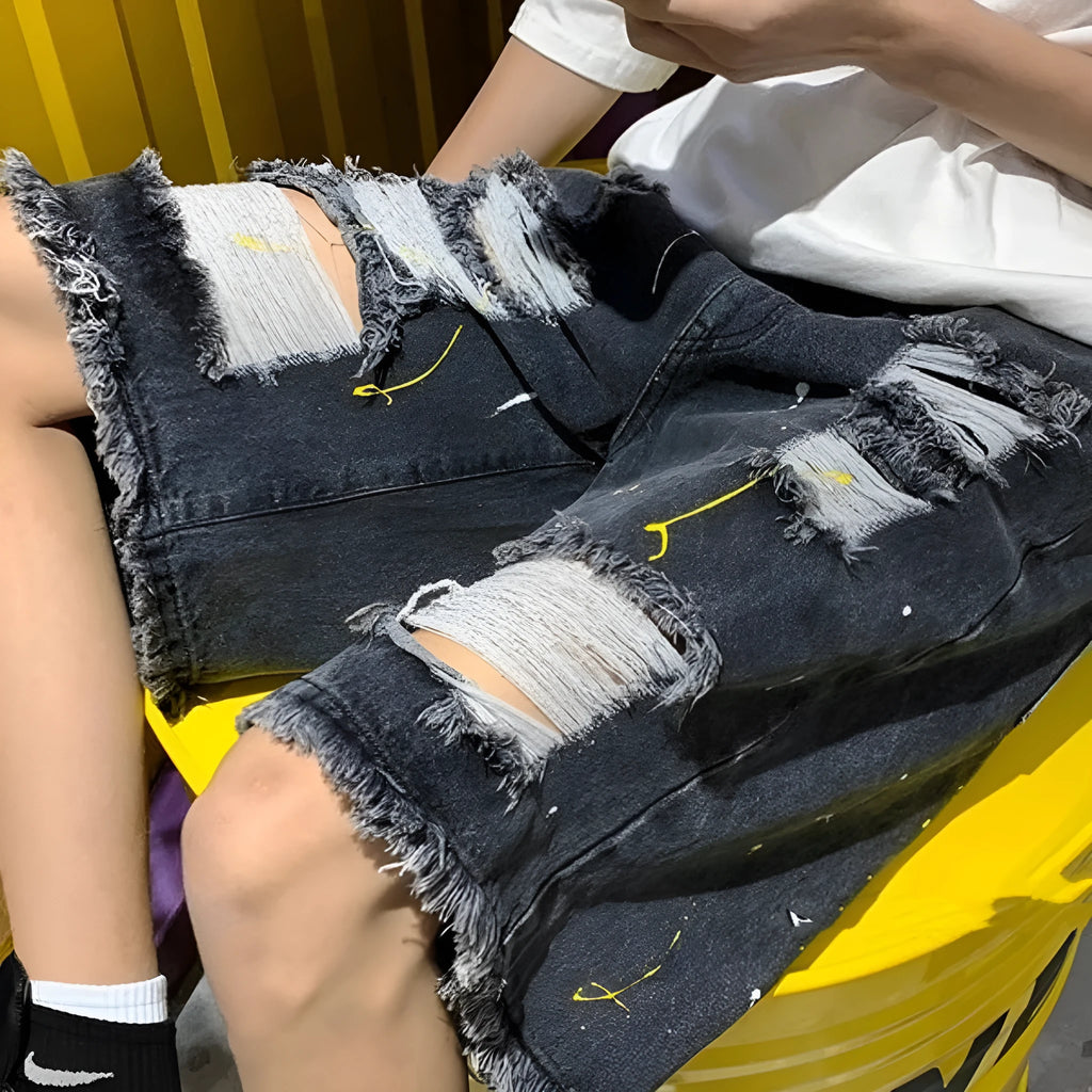 Man wearing loose light blue denim shorts with a distressed hole detail and water-washed finish.
