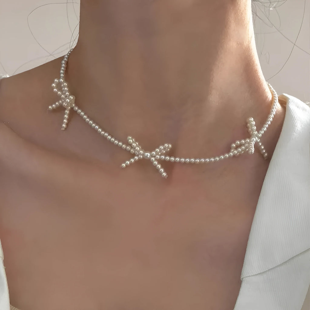 White geometric bow detail on an adjustable imitation pearl necklace for women, chain length 31-40cm.