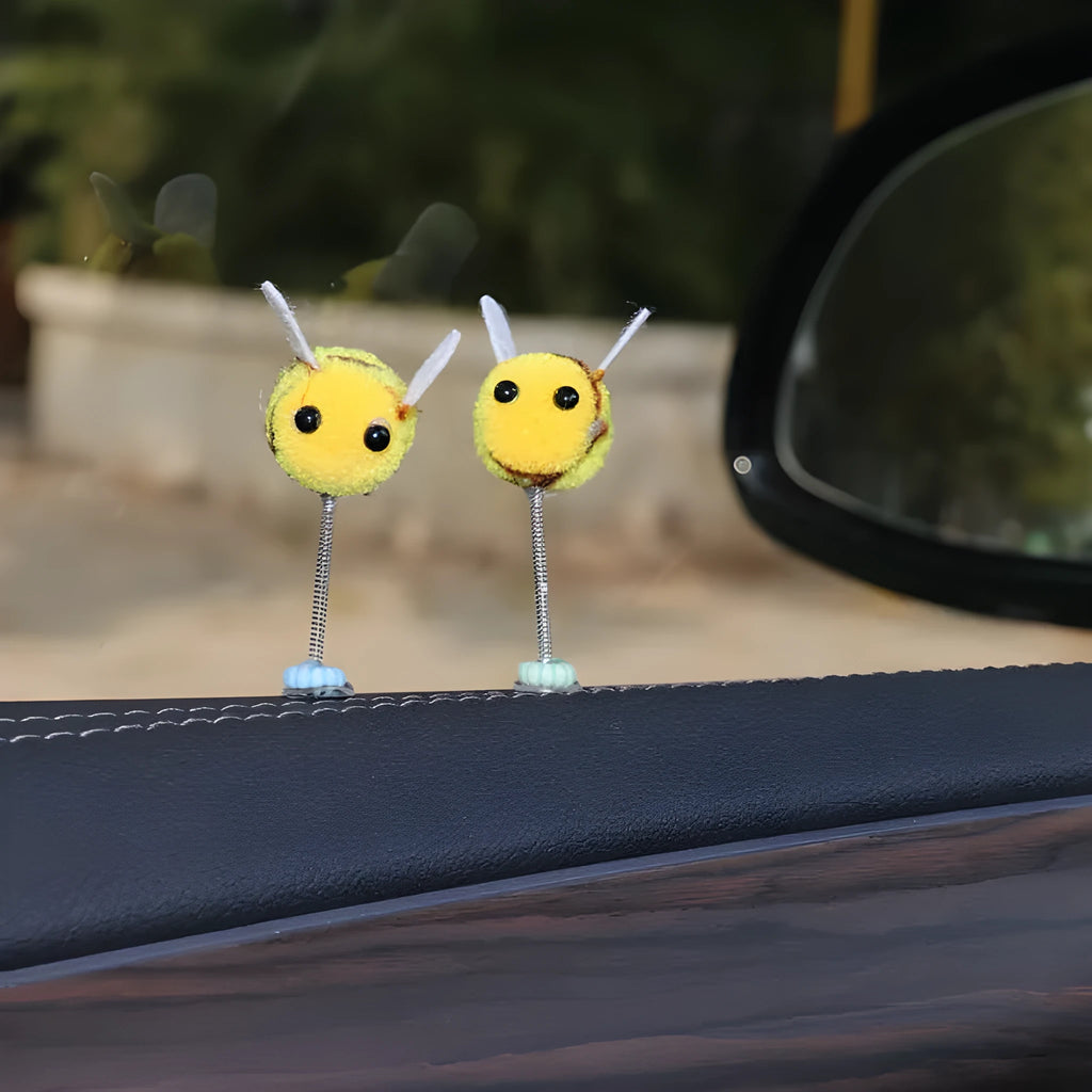 Small yellow and black fur ball bee car decoration on a plastic surface.