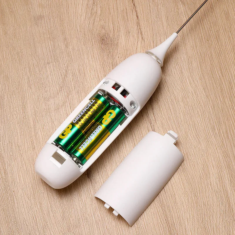 Black and white handheld electric milk frother and blender on a kitchen counter.