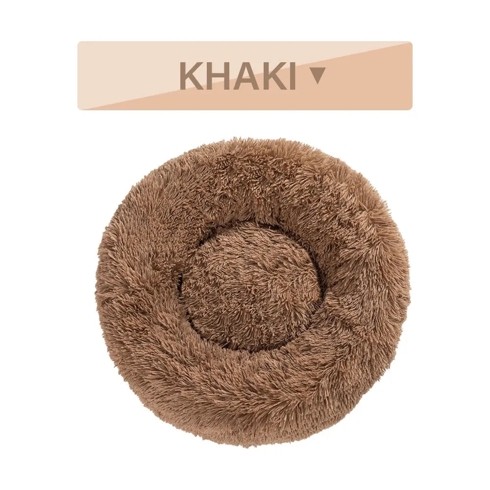 Fluffy donut-shaped dog bed in light grey plush material, showing raised rim and central cushion.