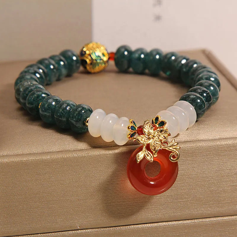 Close-up of a women's crystal bracelet with blue jade beads, red agate, and a silver peace buckle closure.