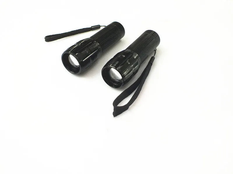 Black mini LED flashlight with telescopic head and tail push button switch on plain background
