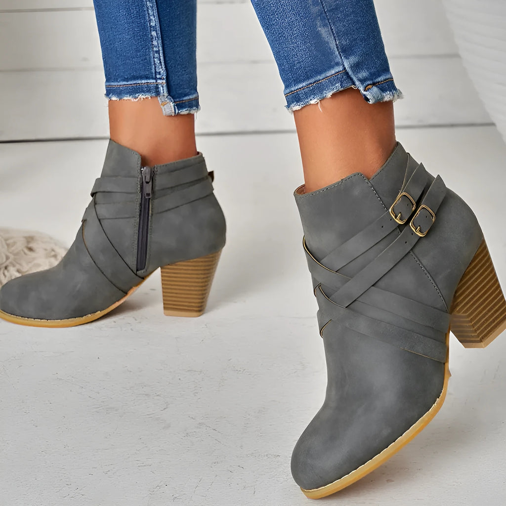 Plus size black short ankle boot with a 7cm heel, side zip, and buckle detail on a grey background.