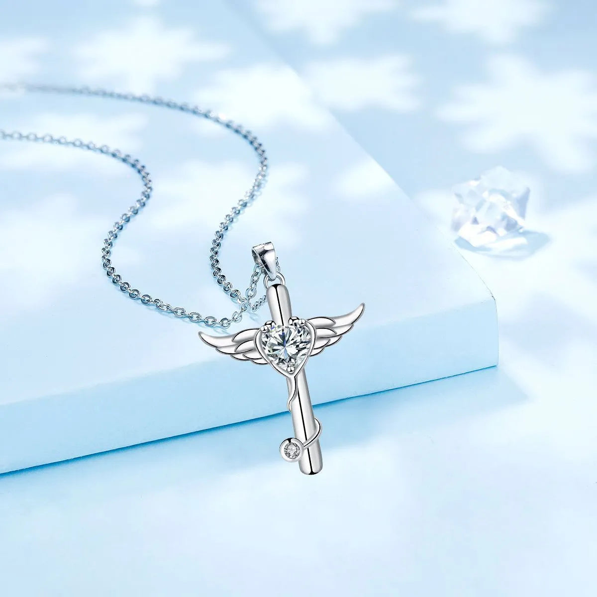 Close-up of a women's necklace with a charm combining a cross, stethoscope, and wings, in a choice of red or white electroplated finish.