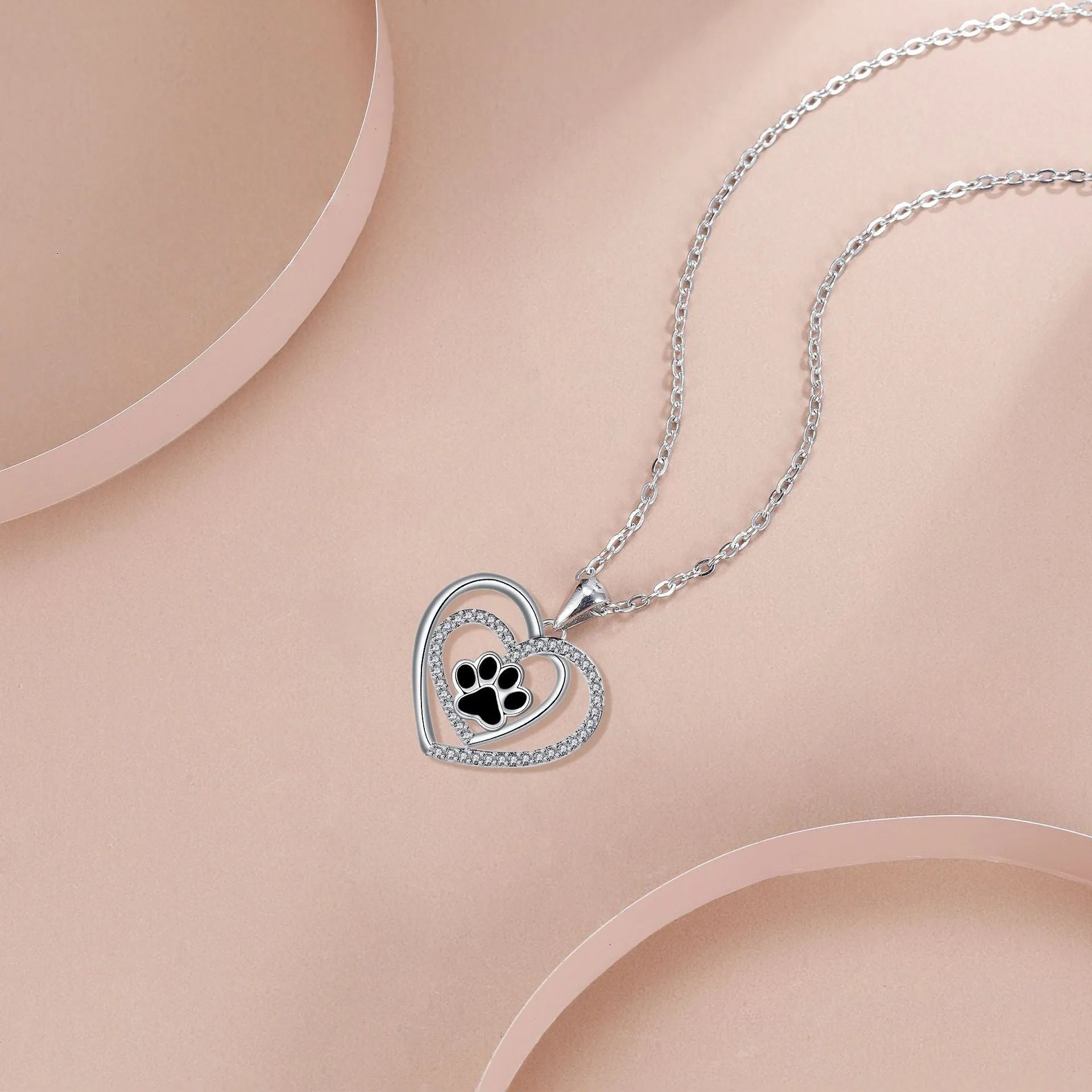 Gold tone dog paw print and heart charm necklace on a cross chain for women.