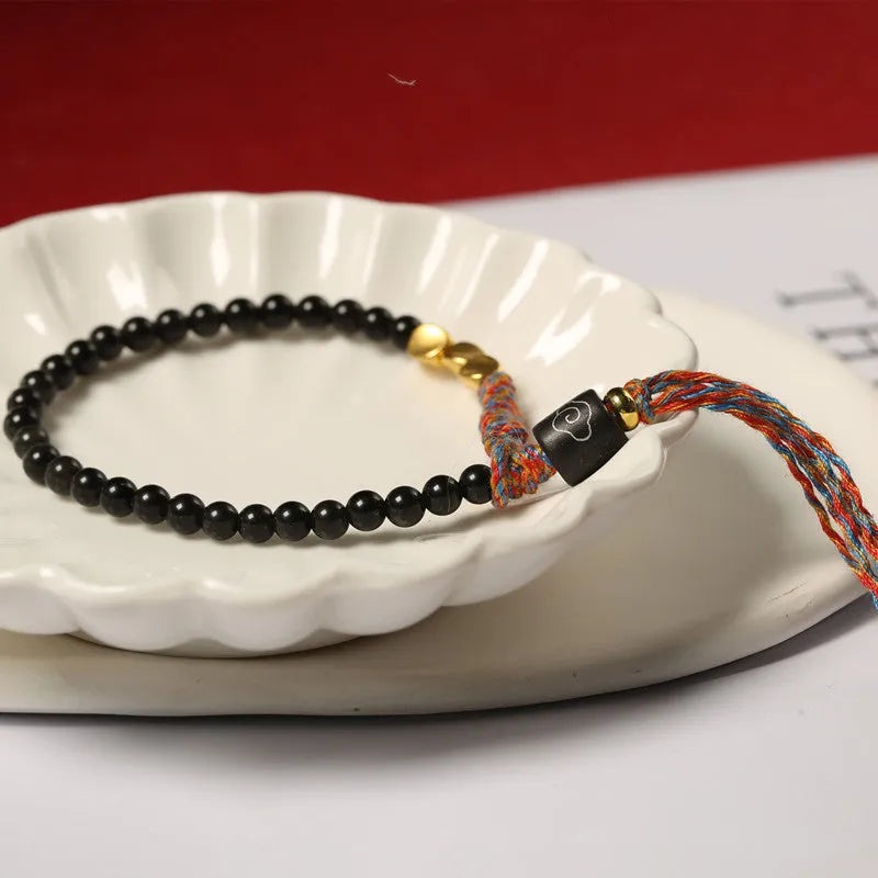 Slender dark obsidian hand-woven bracelet strap shown on a wrist