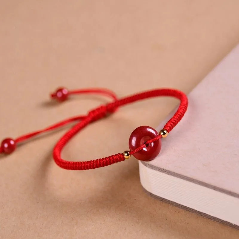 Traditional Chinese cinnabar bracelet with heart-shaped centrepiece and peace buckle clasp on coloured rope cord