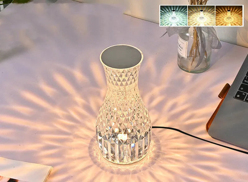 Transparent vase-shaped crystal LED table lamp on a table, showing soft coloured light.
