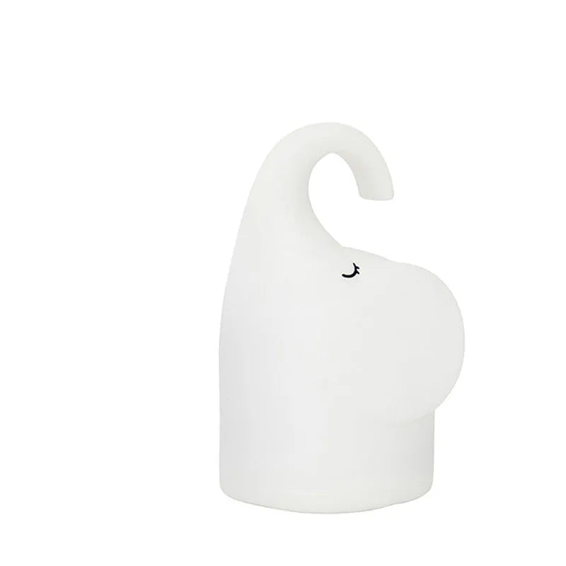 DOMI Elephant shaped silicone night light with warm white LED glow on a bedside table.