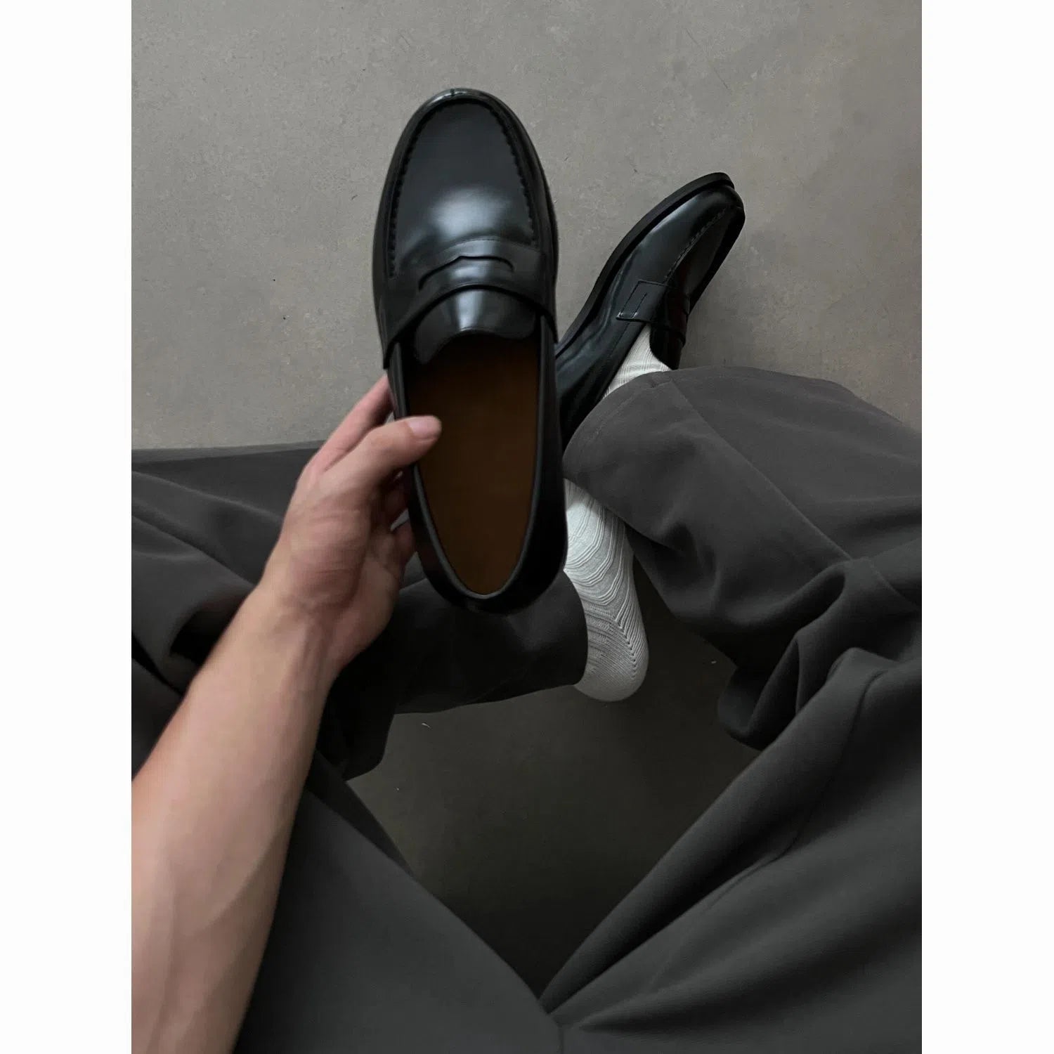 Men's black British-style slip-on leather loafers with stitched seams and vulcanised rubber sole on a plain background
