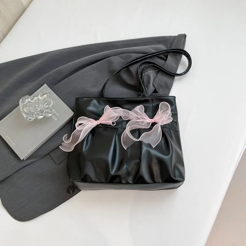 Black college-style tote bag with large capacity, a bow detail, and two shoulder straps.