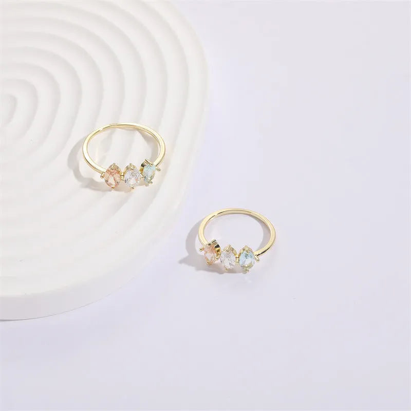Geometric triangle copper ring with horse eye motif, tricolor zircon, and gold electroplate finish.