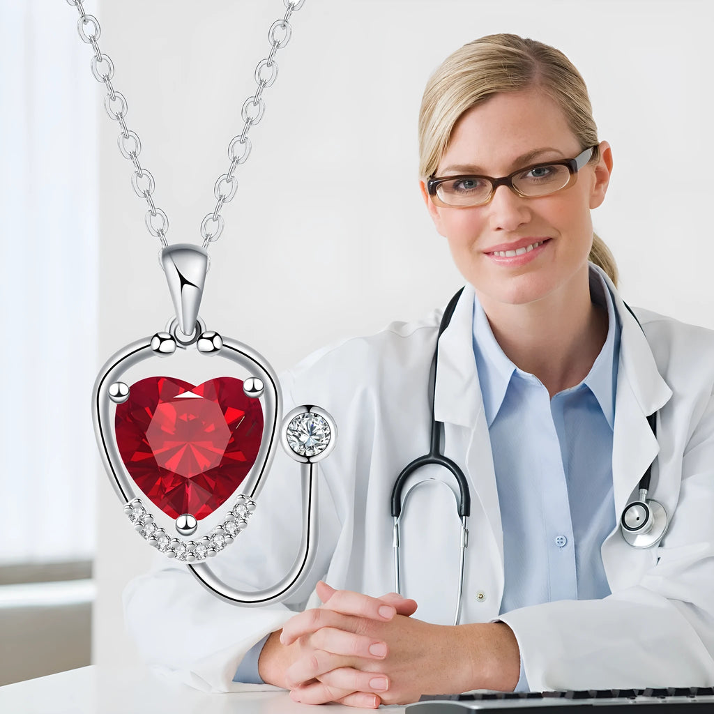 Red diamond stethoscope necklace with a wing and cross pendant on a chain.