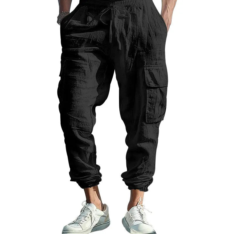 Man wearing loose khaki linen casual trousers with a drawstring waist and ankle-tied legs.