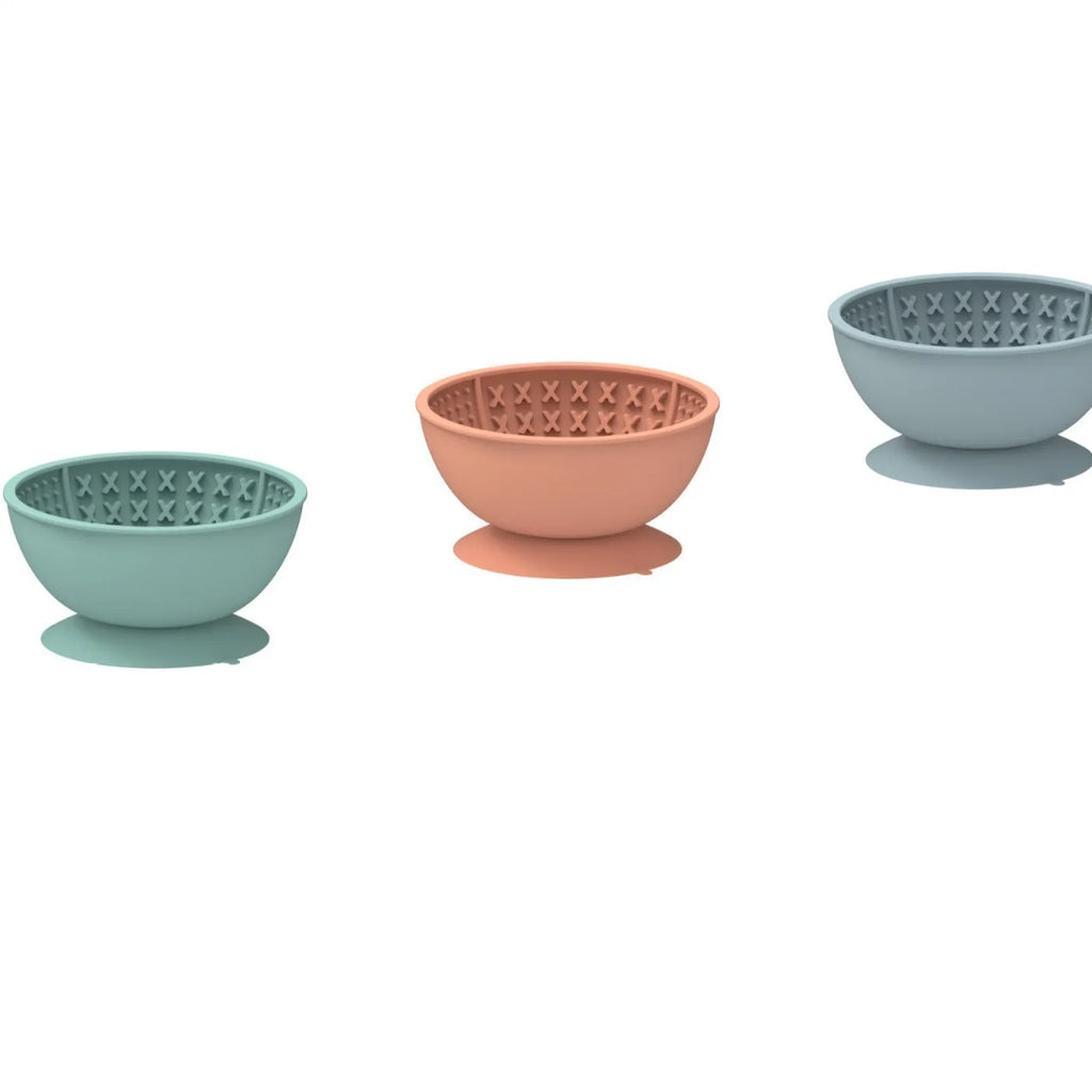 Cyan silicone dog bowl with textured licking mat surface and a suction cup base on a table.