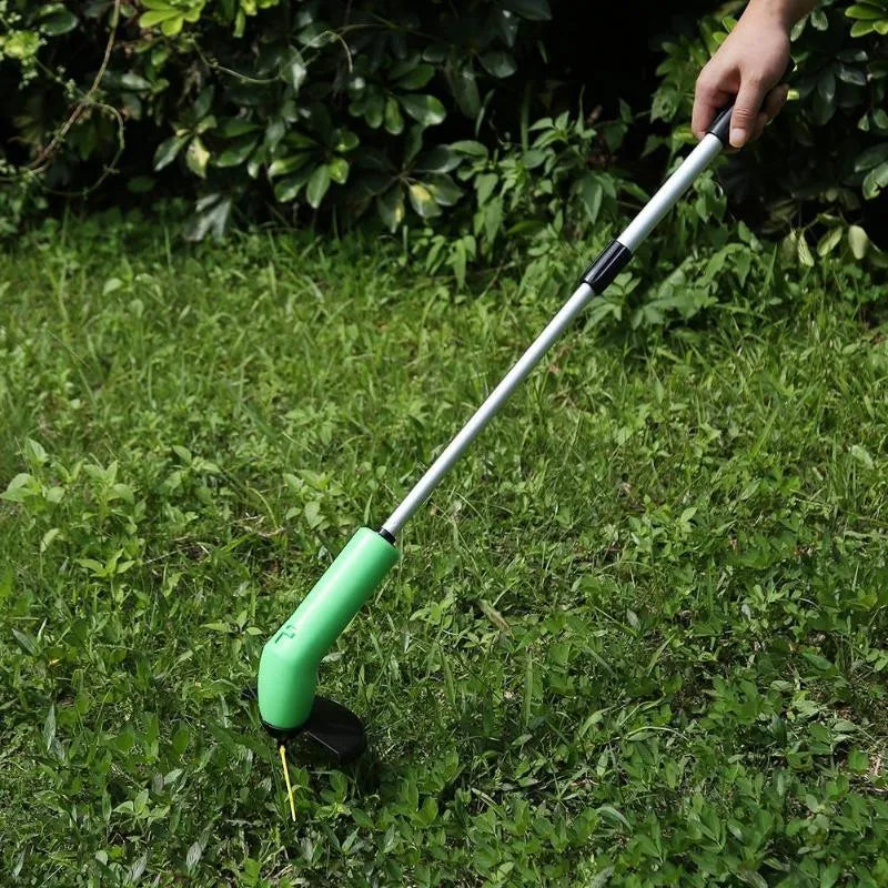 Cordless handheld grass trimmer with extension pole and protective shield on a garden lawn