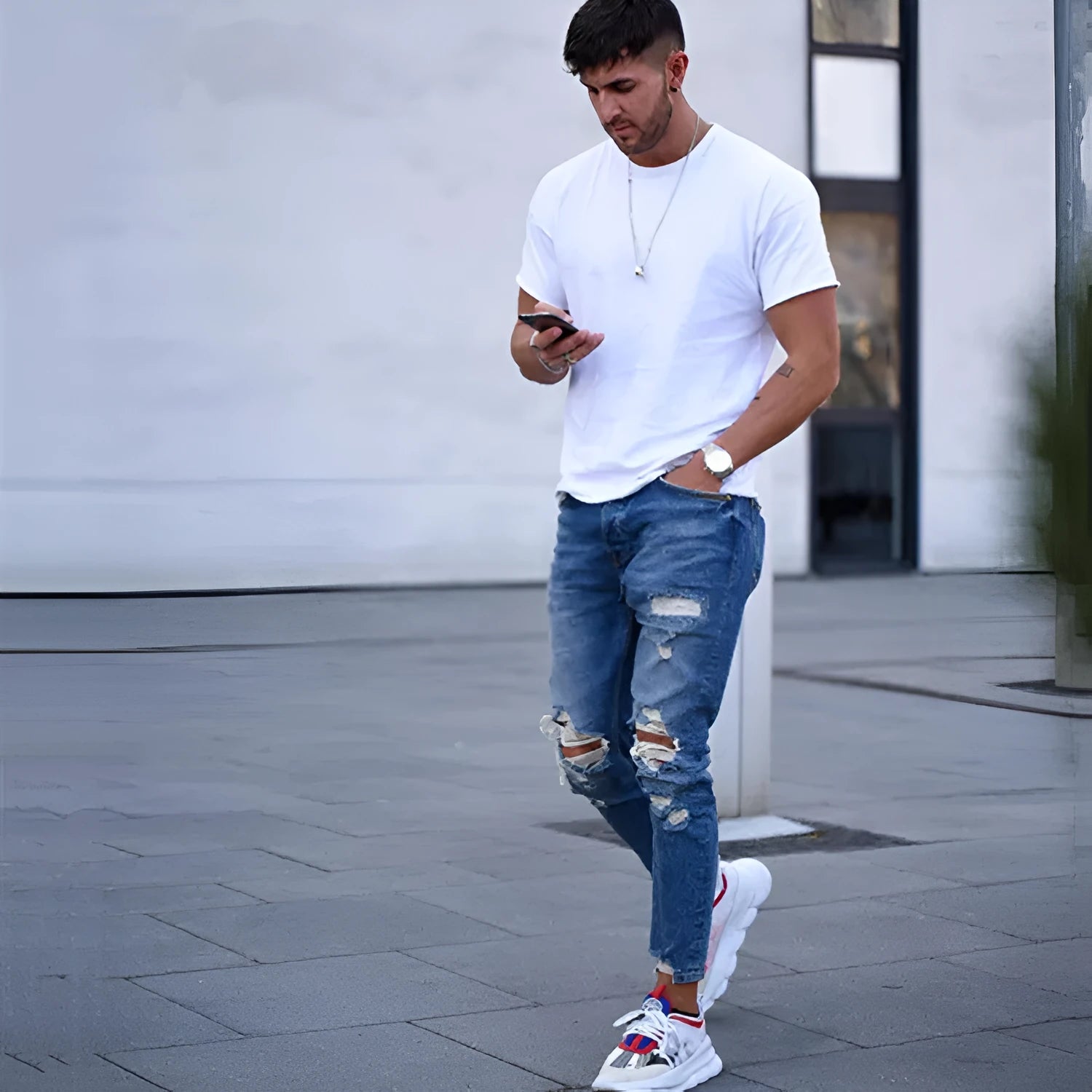 Men's deep blue cotton jeans with a distressed hole design laid flat.