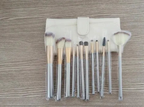 Persian makeup brush set with rice white bristles and champagne coloured handles laid out in rows.