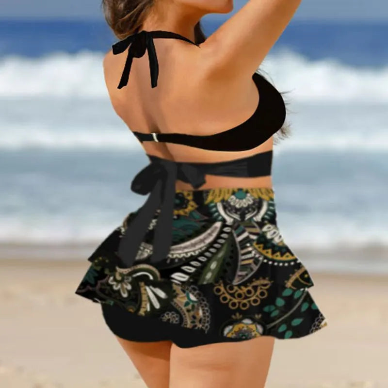 Women's black bikini set with lace-up detail and matching split skirt laid flat.
