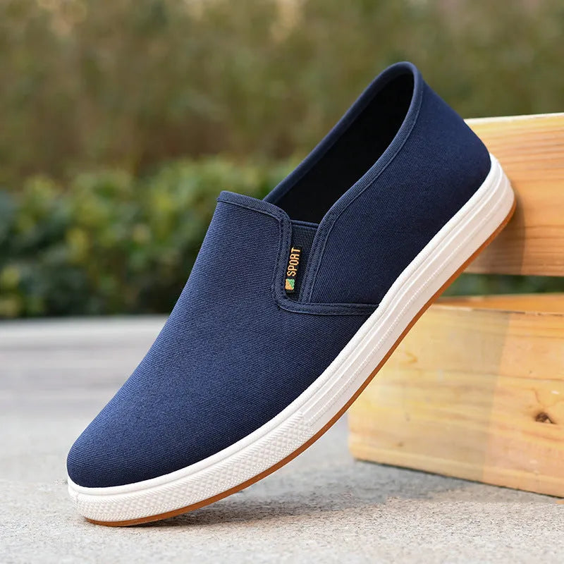 Men's black slip-on canvas trainers with round toe and low-top design on a white background