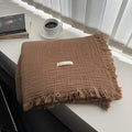 Four-layer gauze cotton blanket with tassel trim in navy blue colour, laid flat.