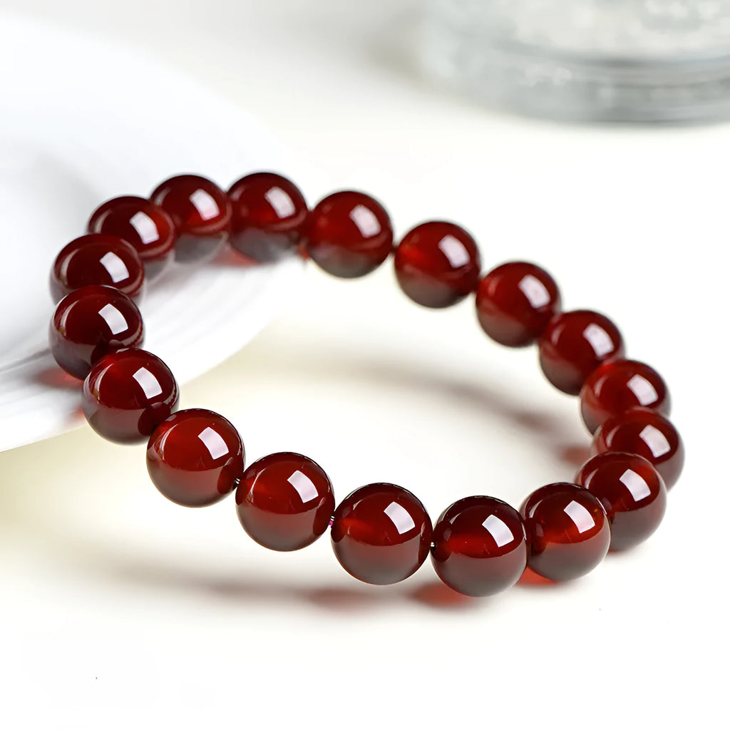 Natural orange red garnet crystal bracelet with Ruyi charms on a white background.