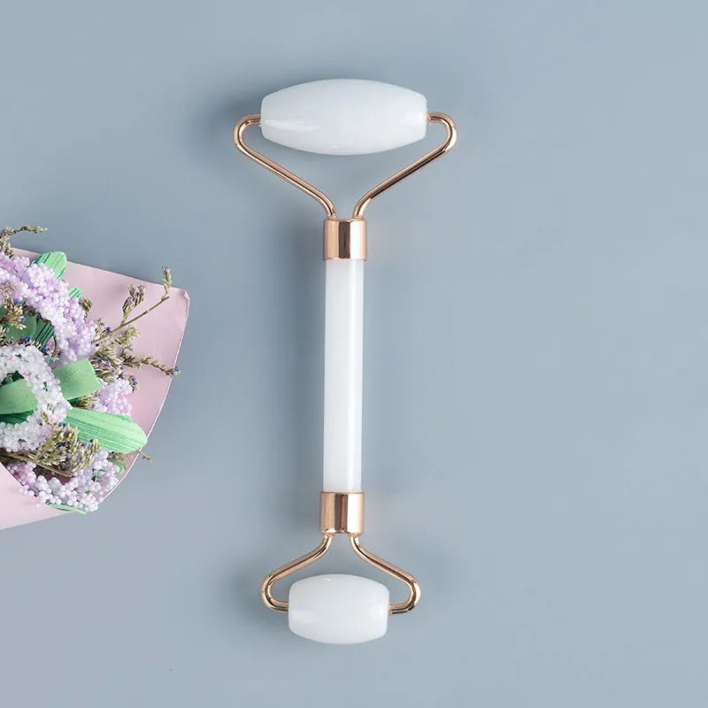 White jade double-headed facial roller and gua sha board set on a flat surface.