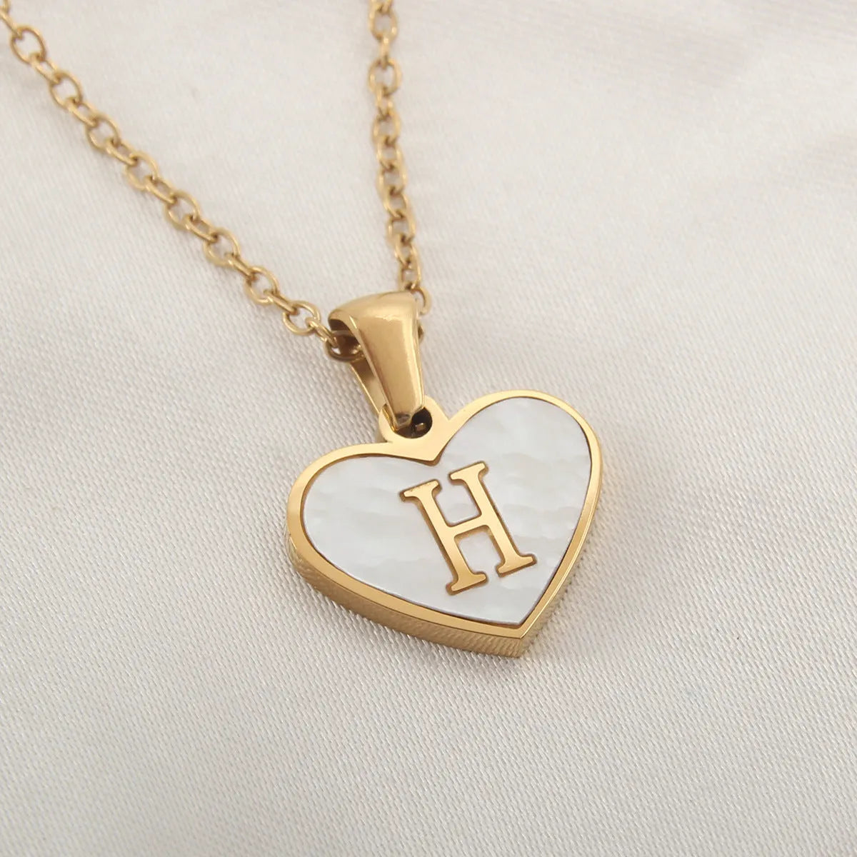 Gold plated chain necklace with a white shell heart-shaped pendant personalised with a single letter initial.