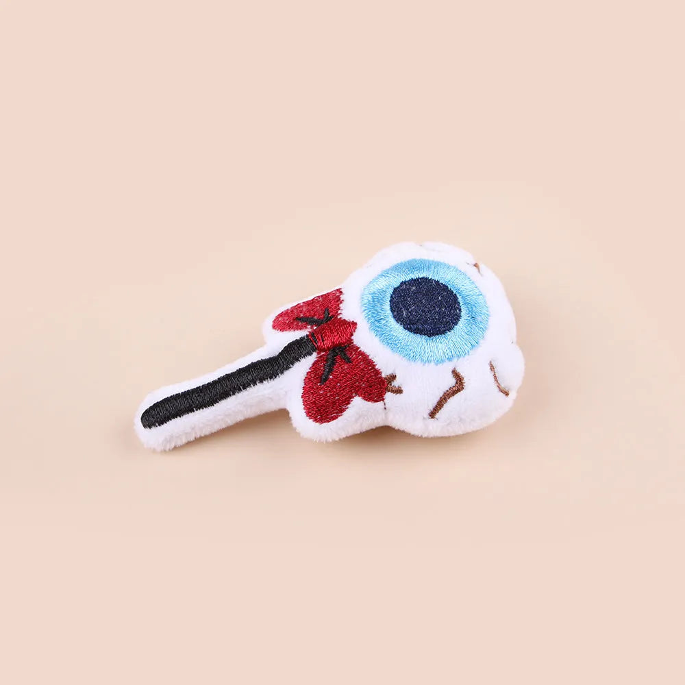Plush cat teaser toy with candy, eyes and skull attachments on handheld wand