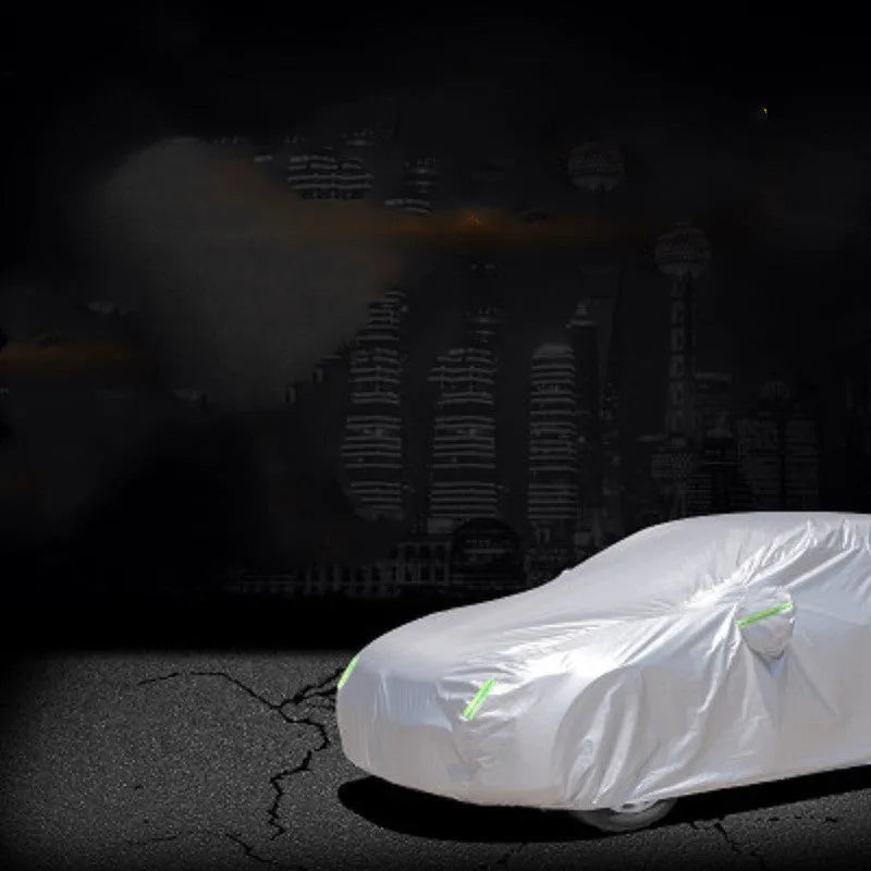 Silver-coated black taffeta universal car cover fitted over a sedan in outdoor parking