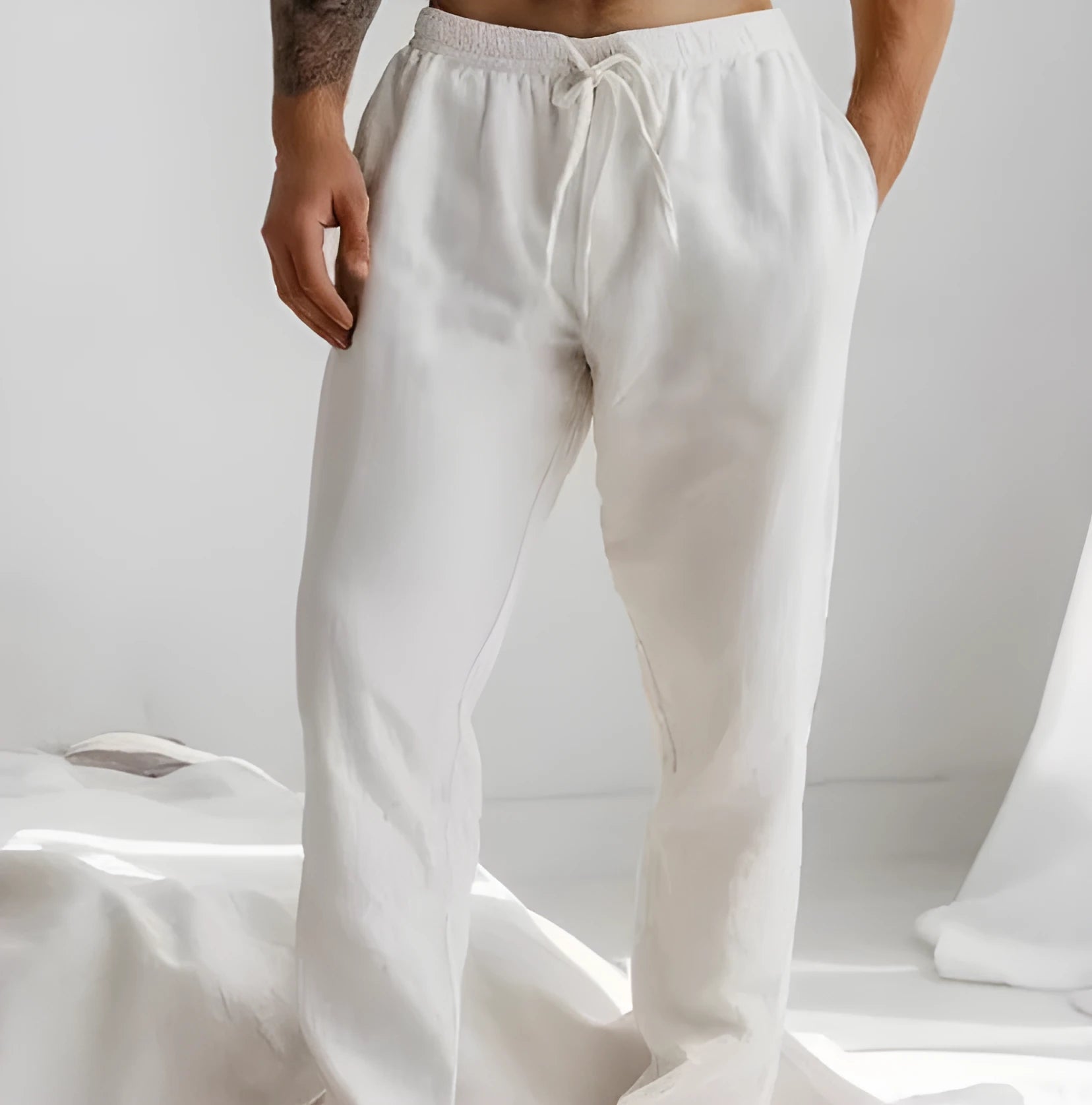 Men's light grey loose-fit cotton linen summer trousers with an elastic drawstring waist and straight legs.